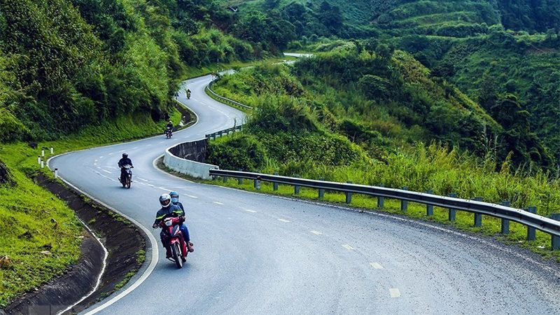 A group of people riding motorcycles on a winding roadDescription automatically generated